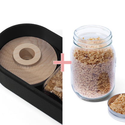 Black 3D Printed container containing a wooden cocktail smoker next to a large glass jar filled withe white oak wood shavings