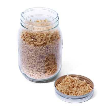 Glass jar with lid containing white oak wood shavings on a white background