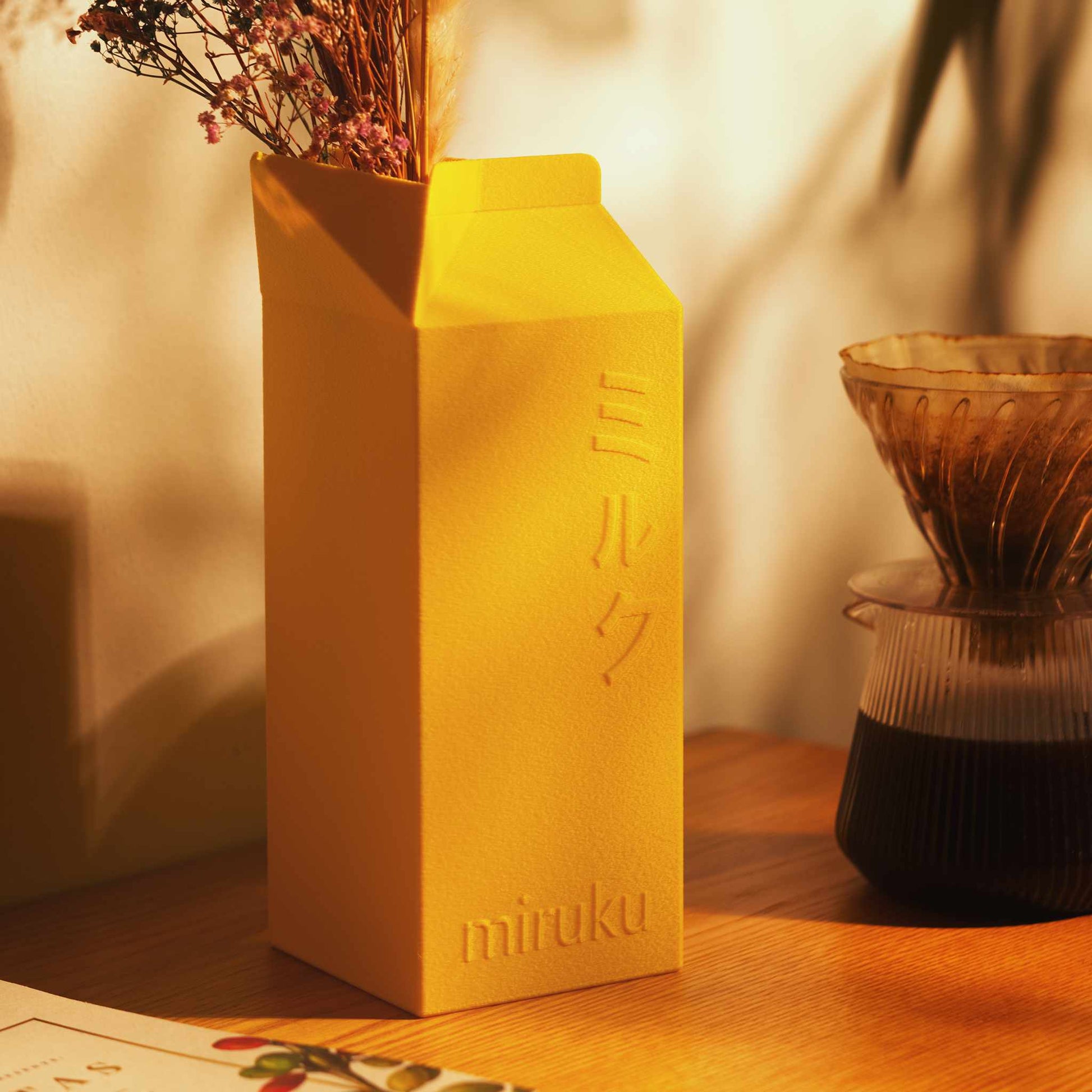yellow 2L milk carton vase holding dried flowers on table