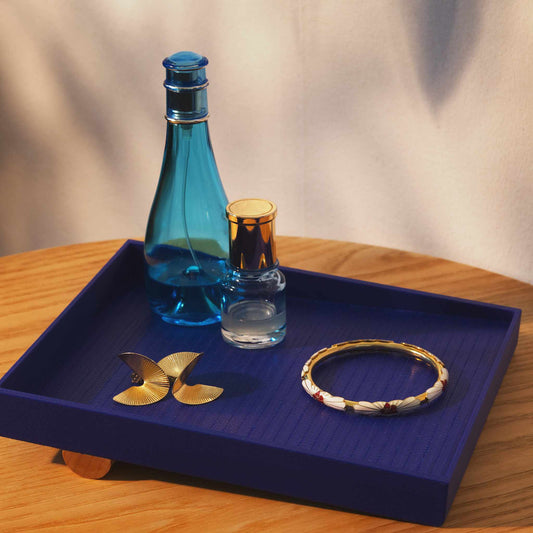 blue catch-all tray with perfume bottles, earrings, and a bracelet displayed on it