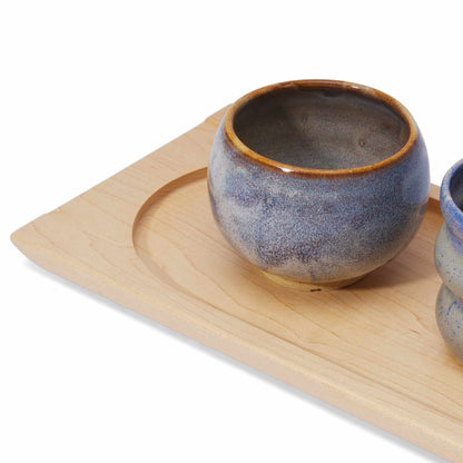 Ceramic cup with brown rim on a handmade wooden tray against a white background