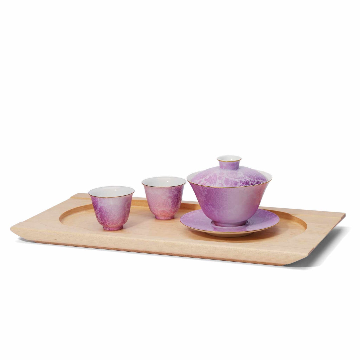 Purple ceramic tea set with two cups and a teapot on a handcrafted wooden tray against a white background