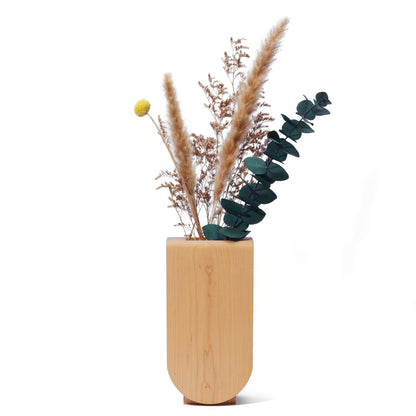 Handmade wooden vase with dried plants in it on a white background
